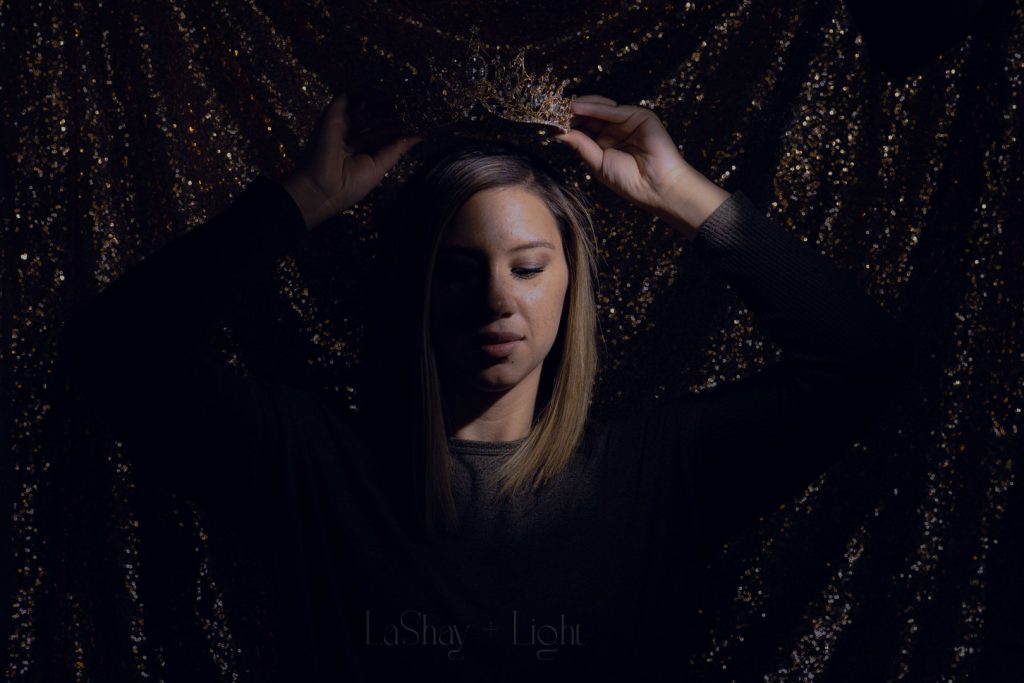 Woman putting on a crown with a dark sequin background
