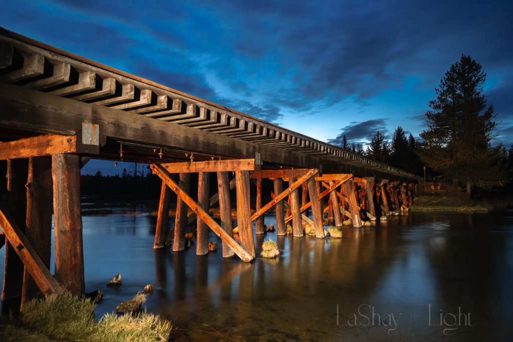 wooden bridge over stream light painting with blue sky island park idaho
