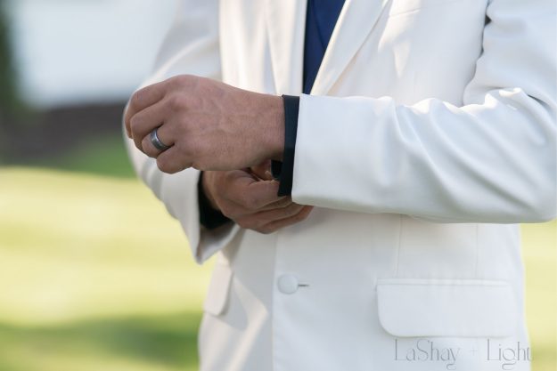wedding detail shot of groom fixing his white sleeve