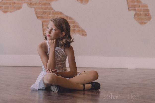 A young ballerina sitting and looking at the light