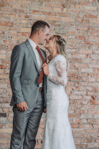 couple about to kiss at wedding with brick wall behind them eloping vs. wedding