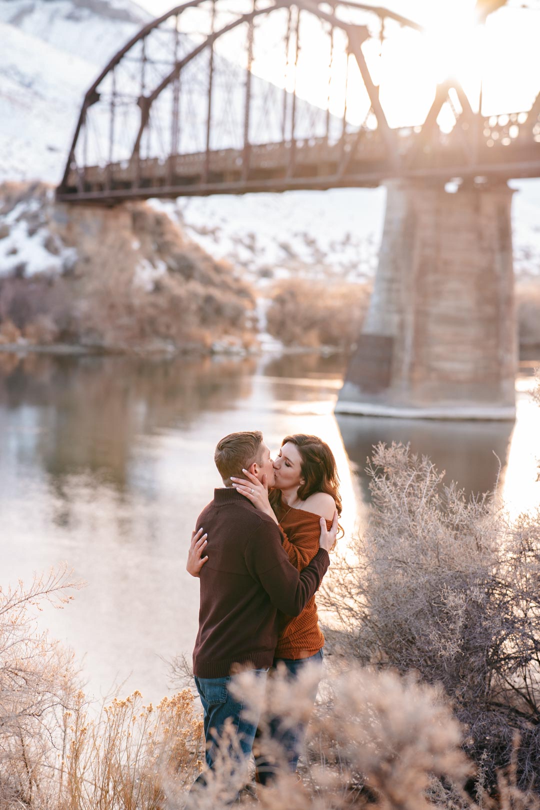 winter engagement session by bridge romantic couple kissing idaho photographer