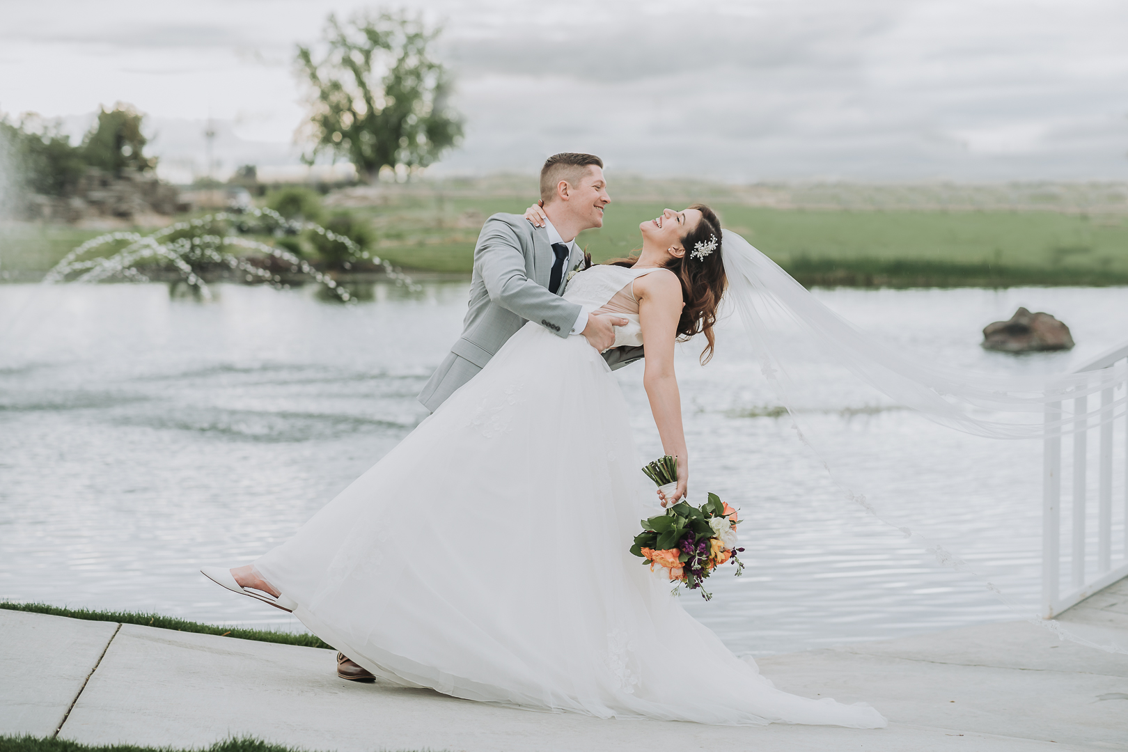 groom dipping smiling bride by lake boise wedding photographer bright and airy